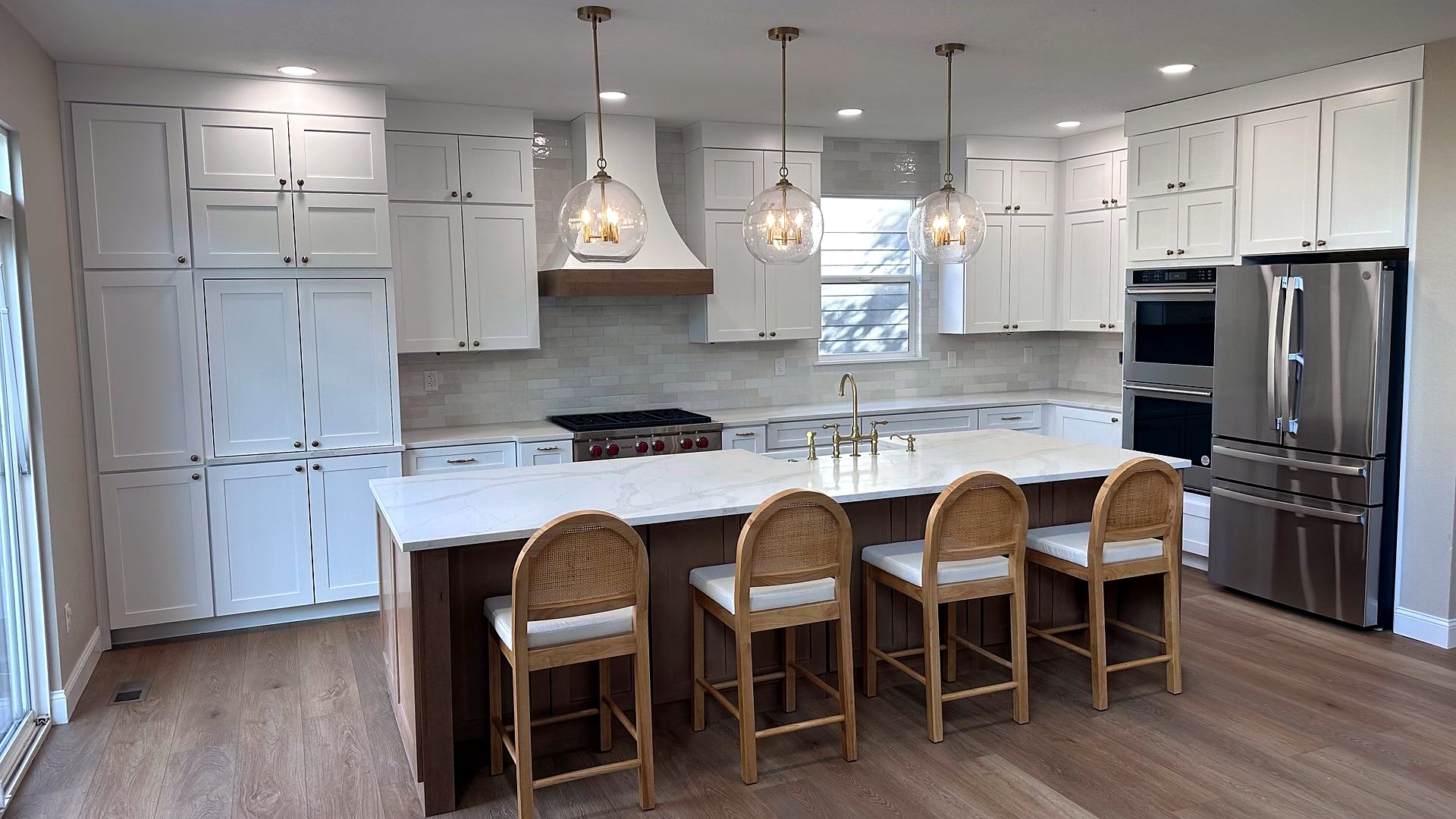 Renovated kitchen with white cabinets, pendant lights and a large island with three seats